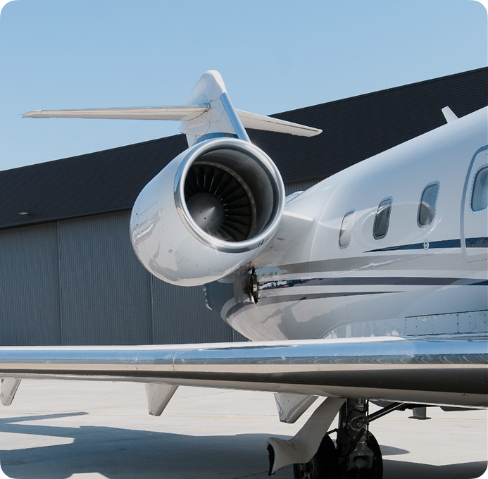 Bombardier Challenger 604 private jet with polished engine and T-tail design parked beside a modern hangar under clear skies.