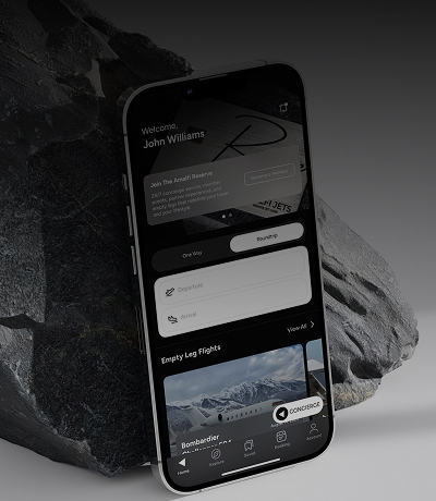 The Amalfi Jets App home page displayed on an iphone leaned against a grey rock.