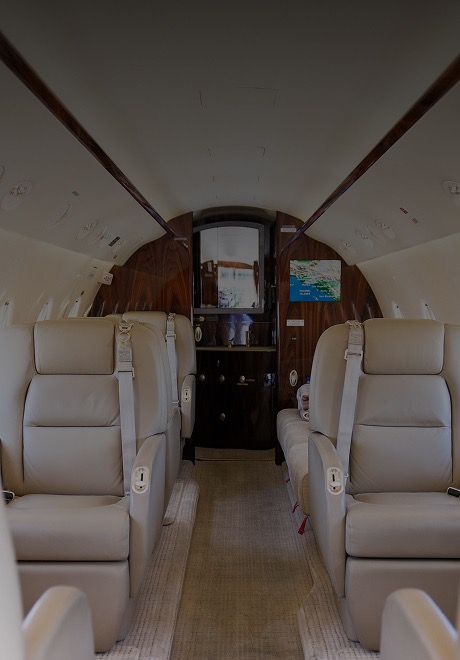 Close-up of a Bombardier Challenger 300 private jet on the tarmac, highlighting its polished engine, swept tail, and sleek silver fuselage.