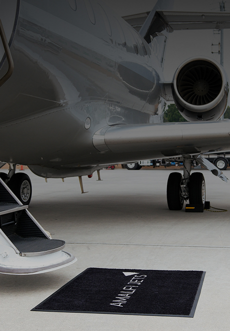 Hawker 900XP private jet with open cabin stairs and polished silver fuselage parked on the tarmac with an Amalfi Jets mat.